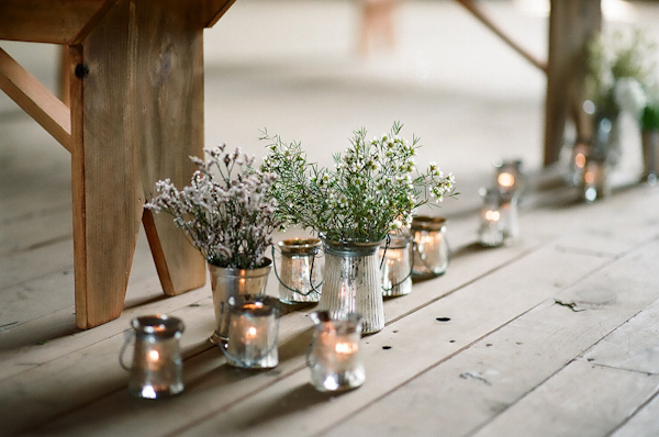 ceremony aisle decor - purple and yellow flowers in rustic tin holders surrounded by candles - photo by North Carolina wedding photographer Richard Israel 